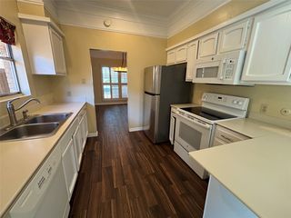 Kitchen featuring wood-finish flooring, white cabinetry, a double basin sink, stainless steel refrigerator, and an electric range with an overhead microwave
