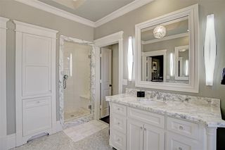 Walk-in shower in the master bathroom, along with marble counters and flooring, custom lighting, framed mirrors, crown molding, and tray ceilings.
