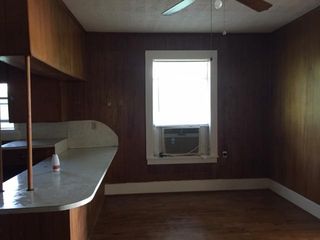 Dining room, window a/c unit, bar, north wall, entrance from living room, paneling with white trim, wood floors
