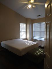 Private bedroom with two windows and blinds, ceiling fan with light, and built-in shelving for everyday storage.