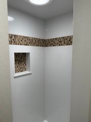 New Quartz solid surface shower with deco accent.