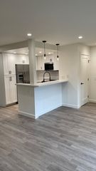 New kitchen with stainless appliances, quartz countertops, recessed lighting, flooring, and doors