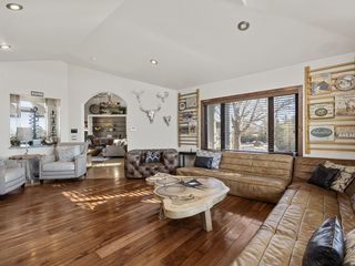 Spacious living room with hardwood floors, ample seating, and large windows with blinds for natural light and privacy.