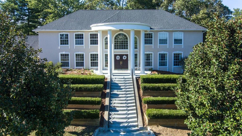 Roy Orbison’s former mansion featuring a grand staircase, manicured hedges, and large white columns at the entrance.